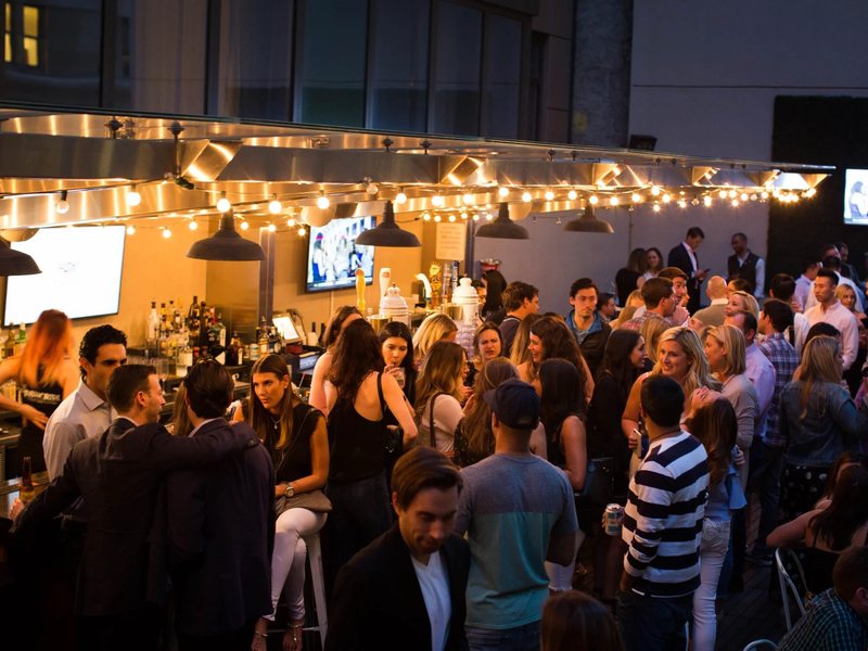 The rooftop packed at night under string lights